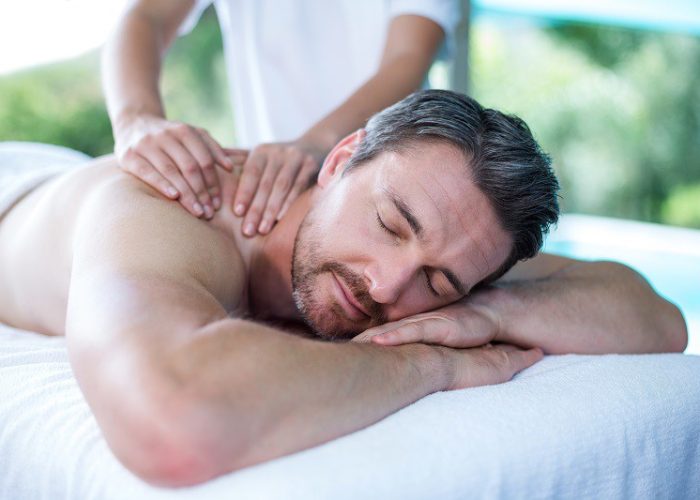 Man receiving back massage from masseur in spa